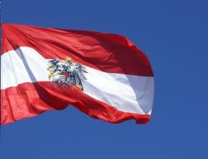 Österreichische Flagge wehend im Wind vor blauem Himmel.
