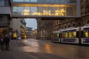 In Bremen laufen verschiedene Personen an einem verregneten Abend durch die Innenstadt, während eine S-Bahn vorbeifährt.