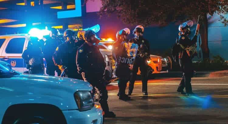 Ein Team aus bewaffneten Polizisten steht bei Dunkelheit auf der Straße und will eine Razzia durchführen