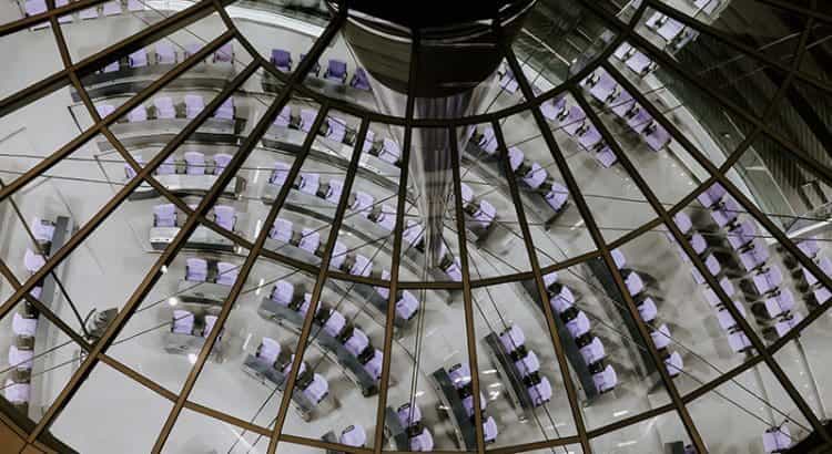 Ein Ausschnitt des Deutschen Bundestags von oben aus der Glaskuppel fotografiert; hell erleuchtet aber menschenleer.