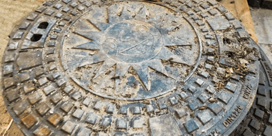 Kanaldeckel mit Merkur-Sonne auf dem Baugelände