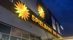 Beleuchtete Fassade der Merkur Spielbank Bad Oeynhausen mit goldenen Merkur-Sonnen am Abend
