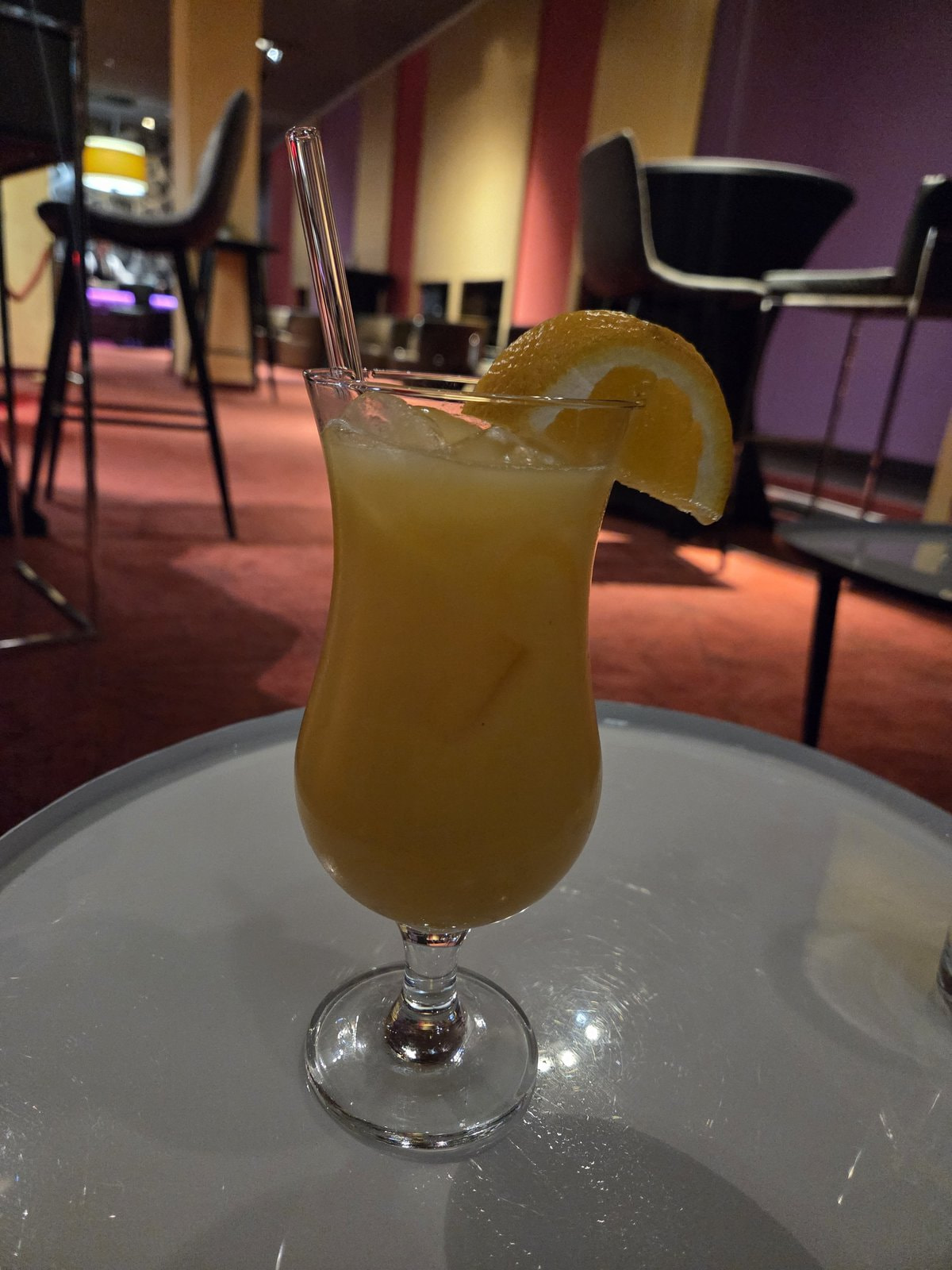 Orangefarbener Cocktail mit Orangenscheibe auf einem Tisch an der Bar