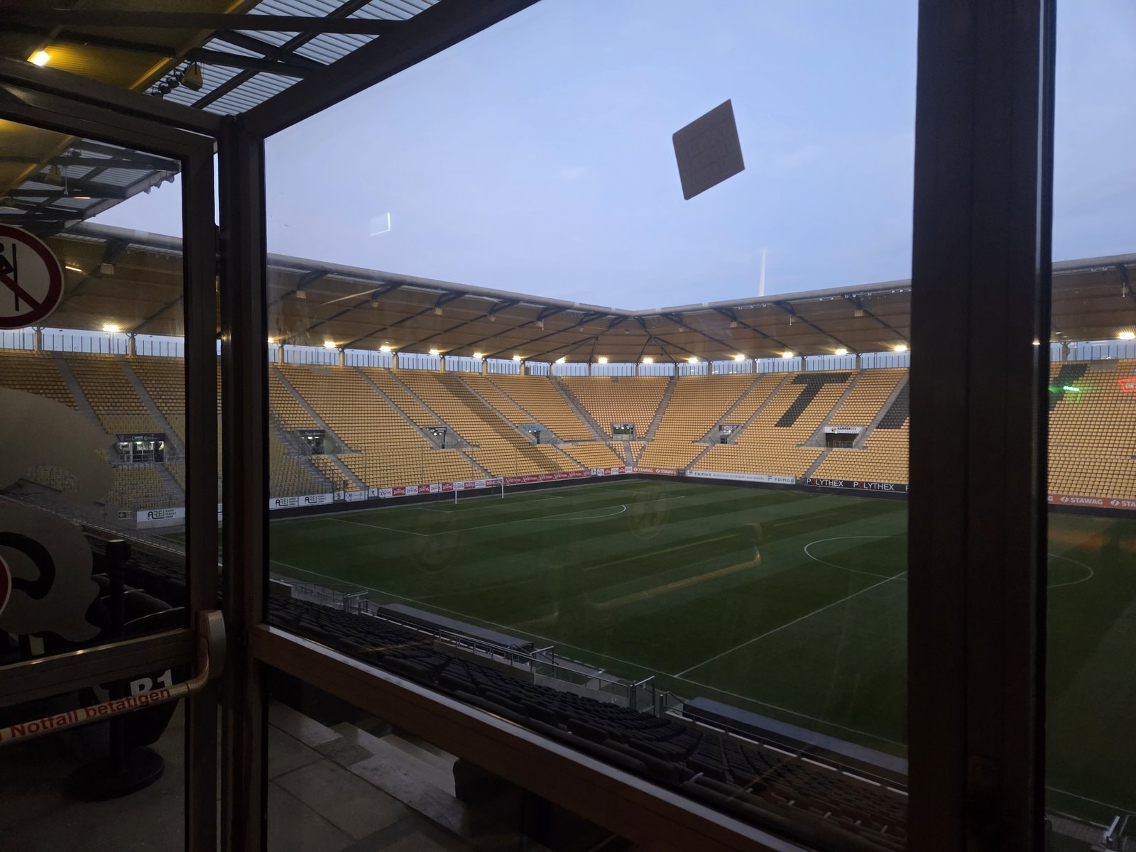 Verglaster Raucherbereich mit Aussicht auf Spielfeld und Tribünen