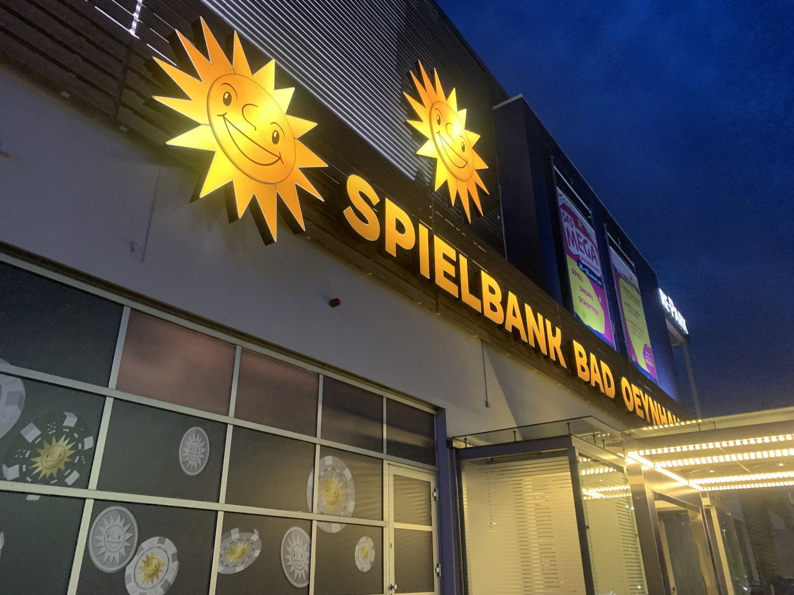 Beleuchteter Schriftzug Spielbank Bad Oeynhausen mit zwei Merkur-Sonnen am Abend