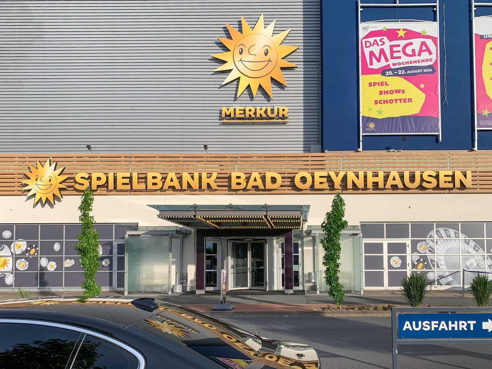 Fassade der Spielbank Bad Oeynhausen bei Tag mit Merkur-Sonne, Eingang und Plakat zum Mega-Wochenende