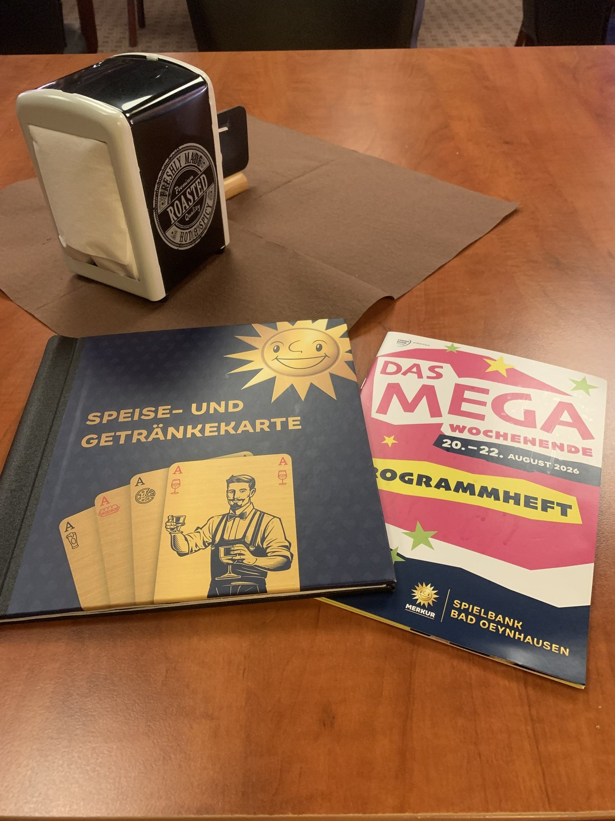 Speise- und Getränkekarte und Programmheft zum Mega-Wochenende auf einem Holztisch der Spielbank Bad Oeynhausen