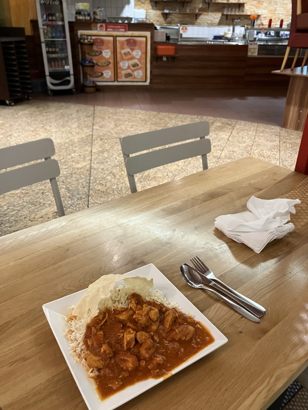 Chicken Tikka Masala mit Reis auf einem Tisch im leeren Food Court der Kurfürstengalerie