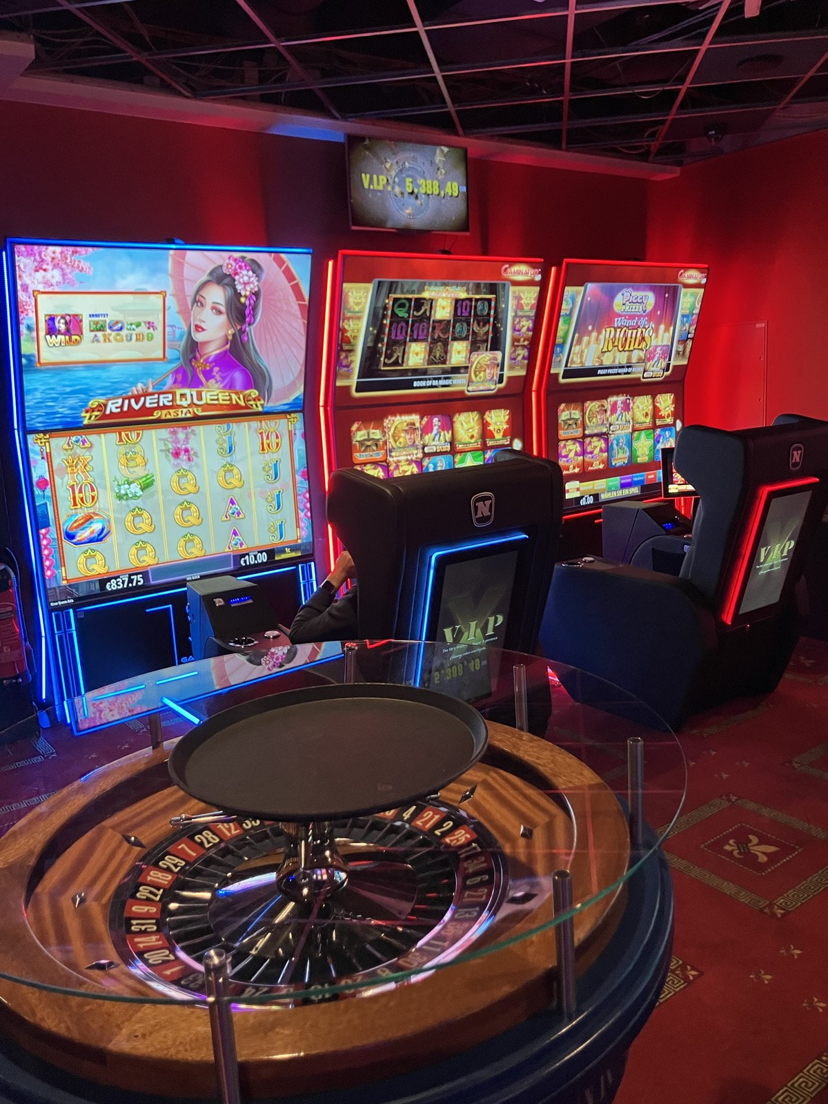 Rot beleuchteter Automatensaal der Spielbank Kassel mit dekorativem Roulettekessel