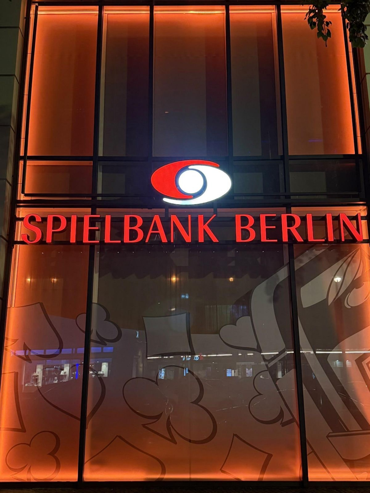 Leuchtschriftzug Spielbank Berlin mit Logo über der orange beleuchteten Glasfassade am Kurfürstendamm