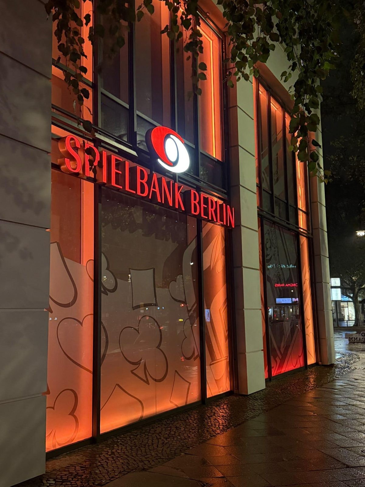 Seitenfassade der Spielbank Berlin am Kurfürstendamm mit Kartensymbolen auf den Fenstern bei Nacht