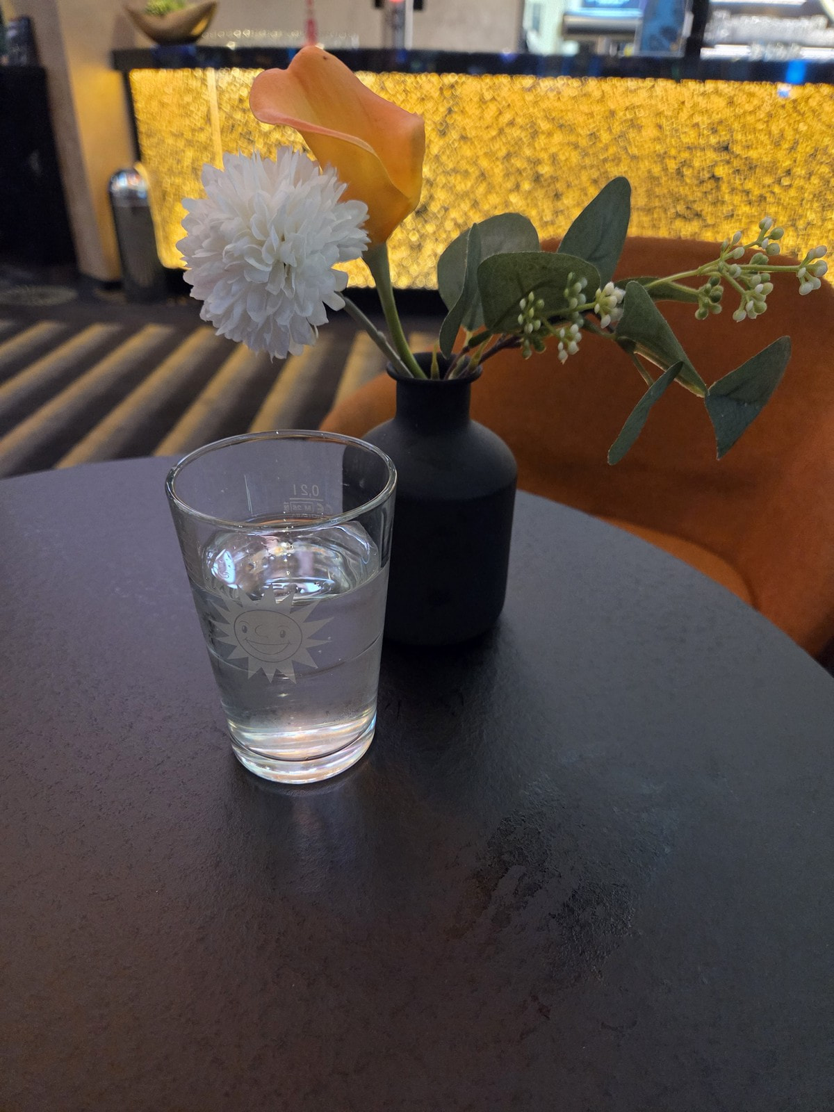 Bartisch mit Blumen und Wasserglas vor der beleuchteten Bar in der Spielbank Monheim