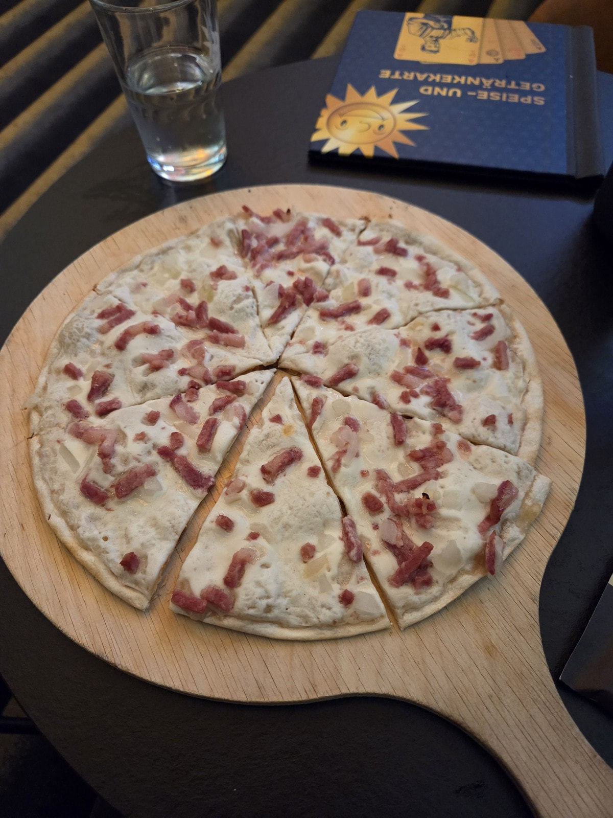 Flammkuchen mit Speck und Zwiebeln auf einem Holzbrett in der Spielbank Monheim