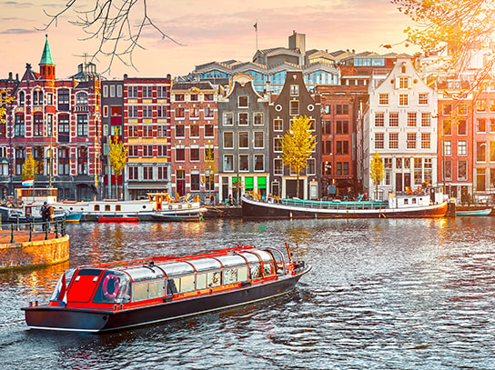 Der Blick auf die Skyline einer Stadt in den Niederlanden, mit eine Fluss und Booten im Vordergrund.